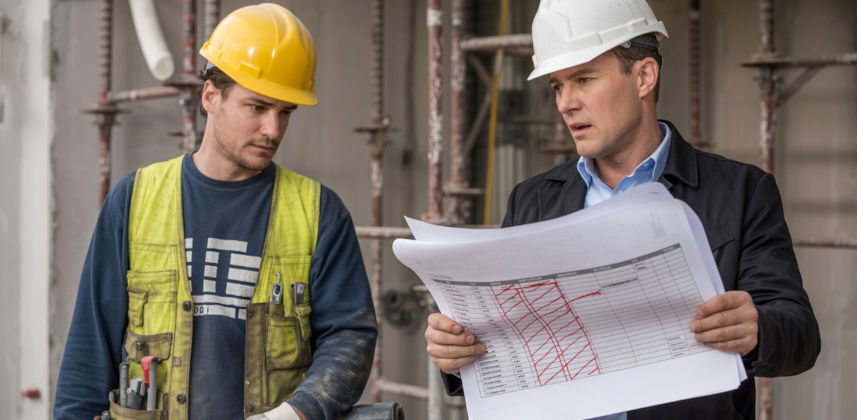 A trades worker on a construction site speaking with a manager
